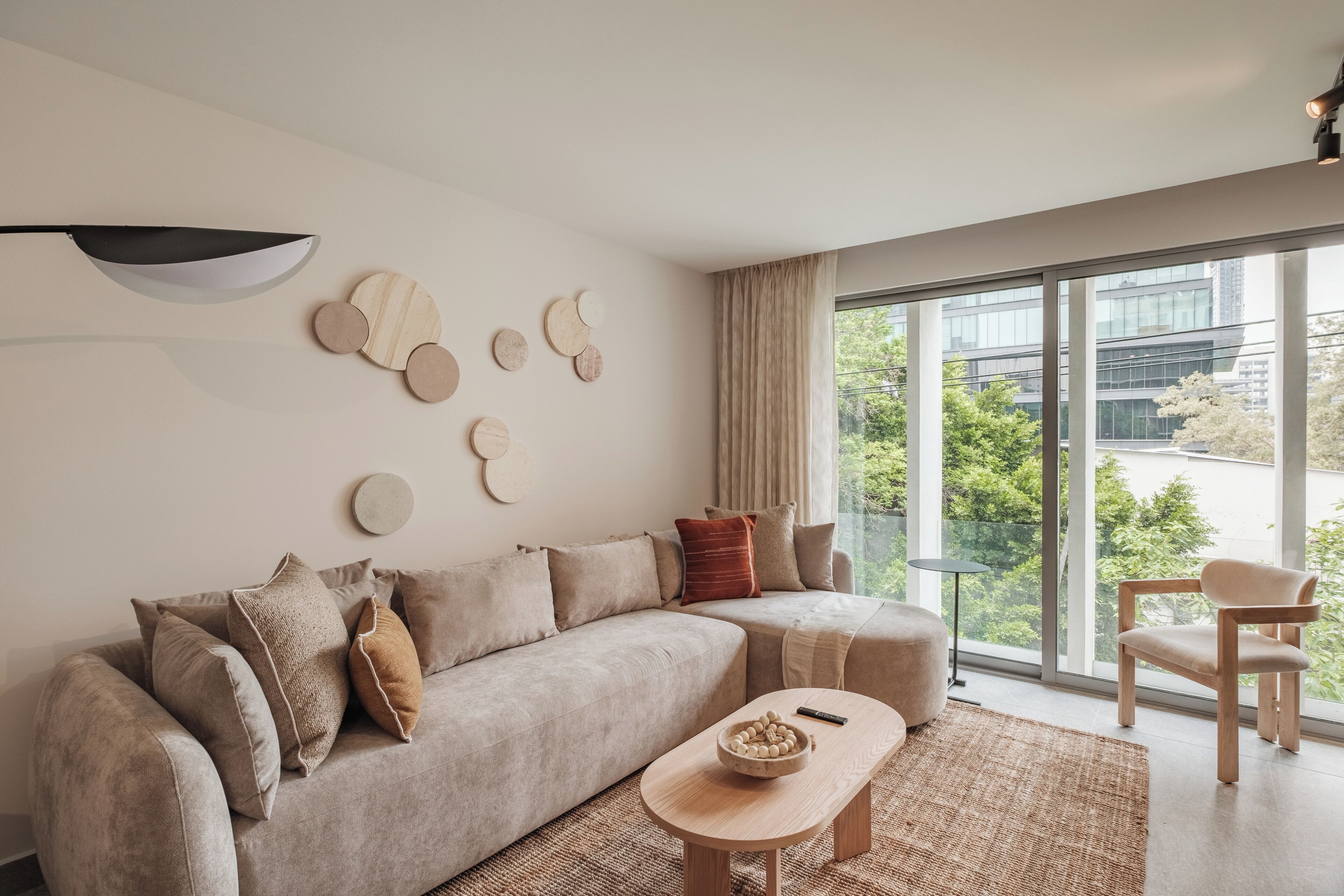 Ein modernes Wohnzimmer mit großem Fenster, einer Couch, einem Couchtisch und einem Sessel.