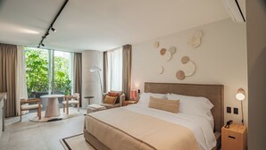 Ein modernes Hotelzimmer mit einem großen Bett, einem runden Couchtisch, einer Couch und einem Esstisch.