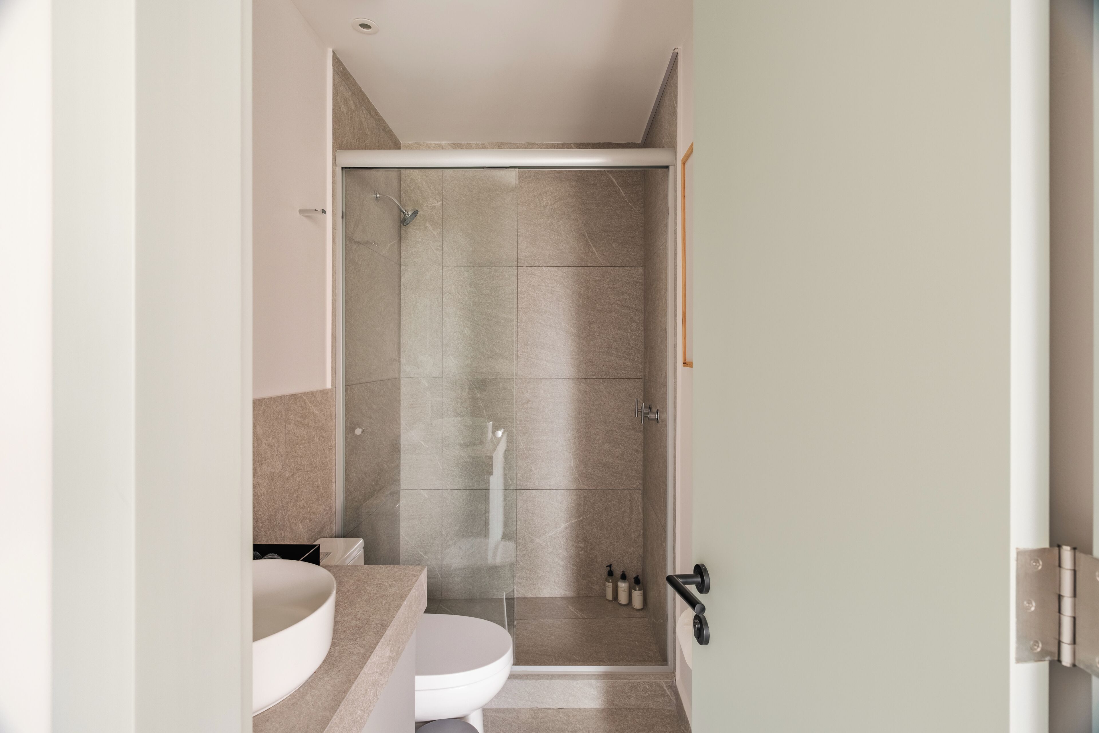 Un baño moderno con inodoro, lavamanos y ducha.