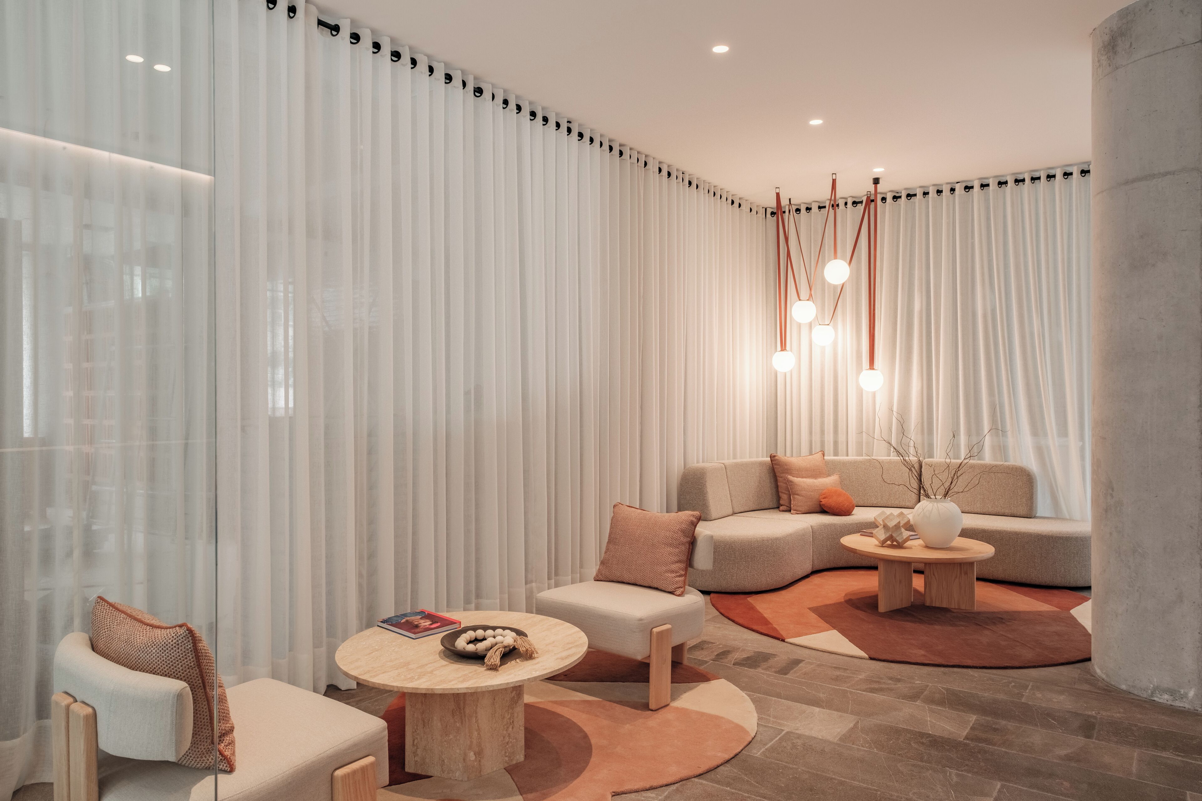 Un salon moderne avec un canapé d’angle, une table basse ronde et une petite table d’appoint.