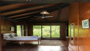 Ein Zimmer mit einem Bett, einem Deckenventilator und großen Fenstern.