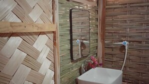 A bathroom with a woven wall design, a mirror, a sink, and a window. - Nisarga Pod House Kaptai (Rajasthali)