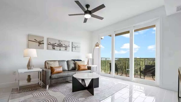 A modern living room with a sofa, coffee table, and artwork on the wall. - River Fly-In Duo - 5Bd - River & Runway View (Merritt Island)