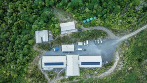 An aerial view of a facility with multiple buildings, parking area, and surrounding dense greenery. - Timber Trail Lodge & Transport (Piropiro)
