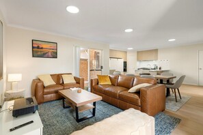 A modern living room with a sofa, coffee table, and TV stand.