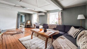 Ein Wohnzimmer mit einer Couch, einem Holztisch, einem Teppich und einem Sessel.