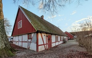 A traditional half-timbered house with a steep gabled roof, a visible chimney, and a gravel driveway.