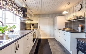 A modern kitchen with a central island, a built-in oven, and a clock on the wall.