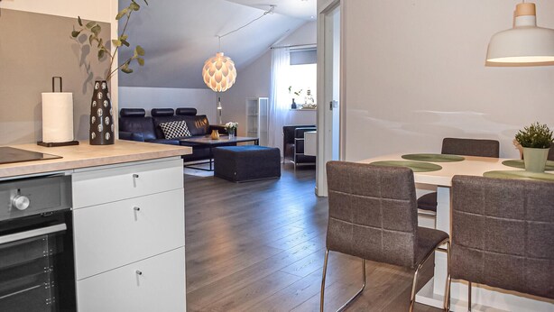 A modern kitchen with a dining area, a sofa, and a pendant light.