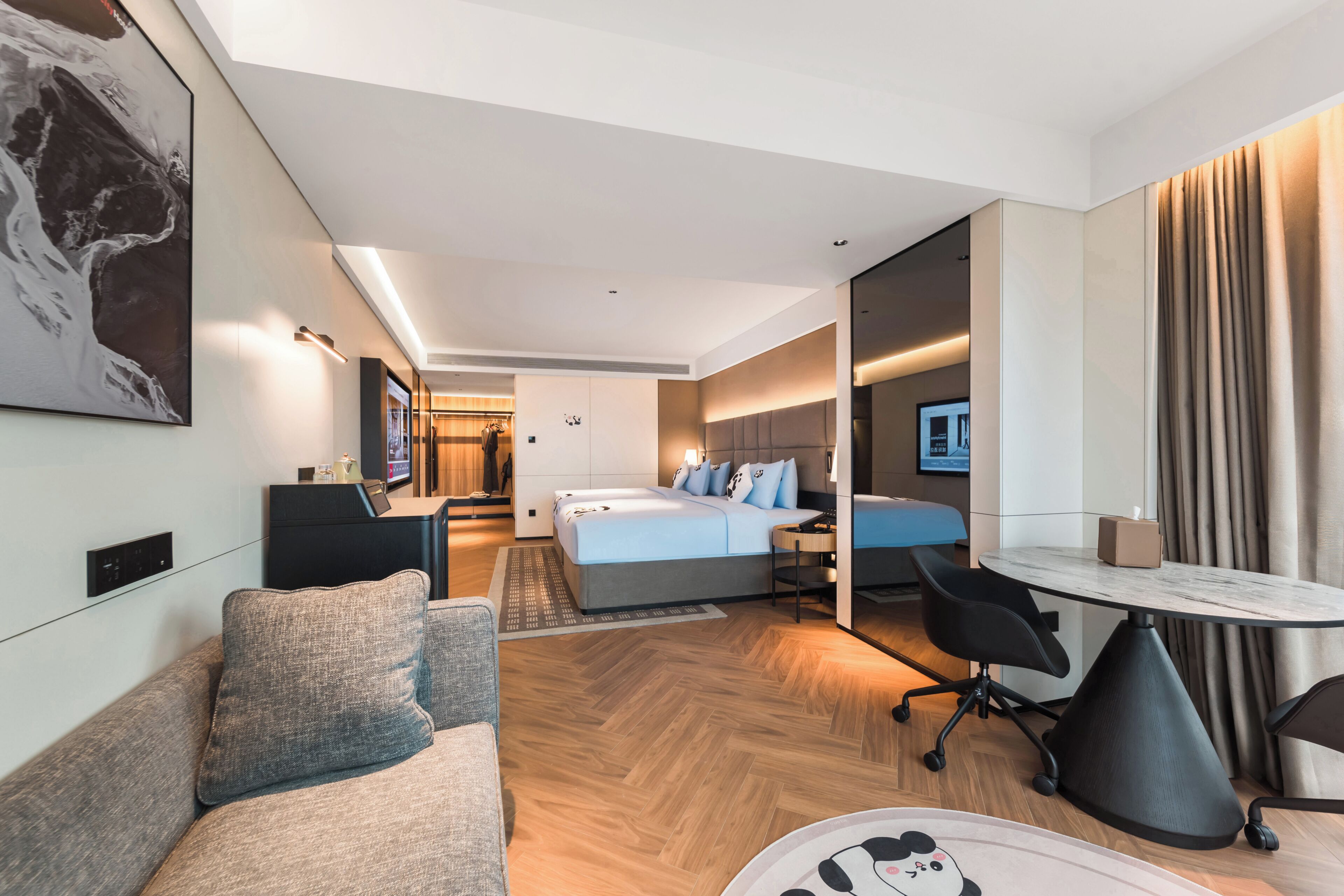 A modern hotel room with a bed, a sofa, a desk, and a dining table.