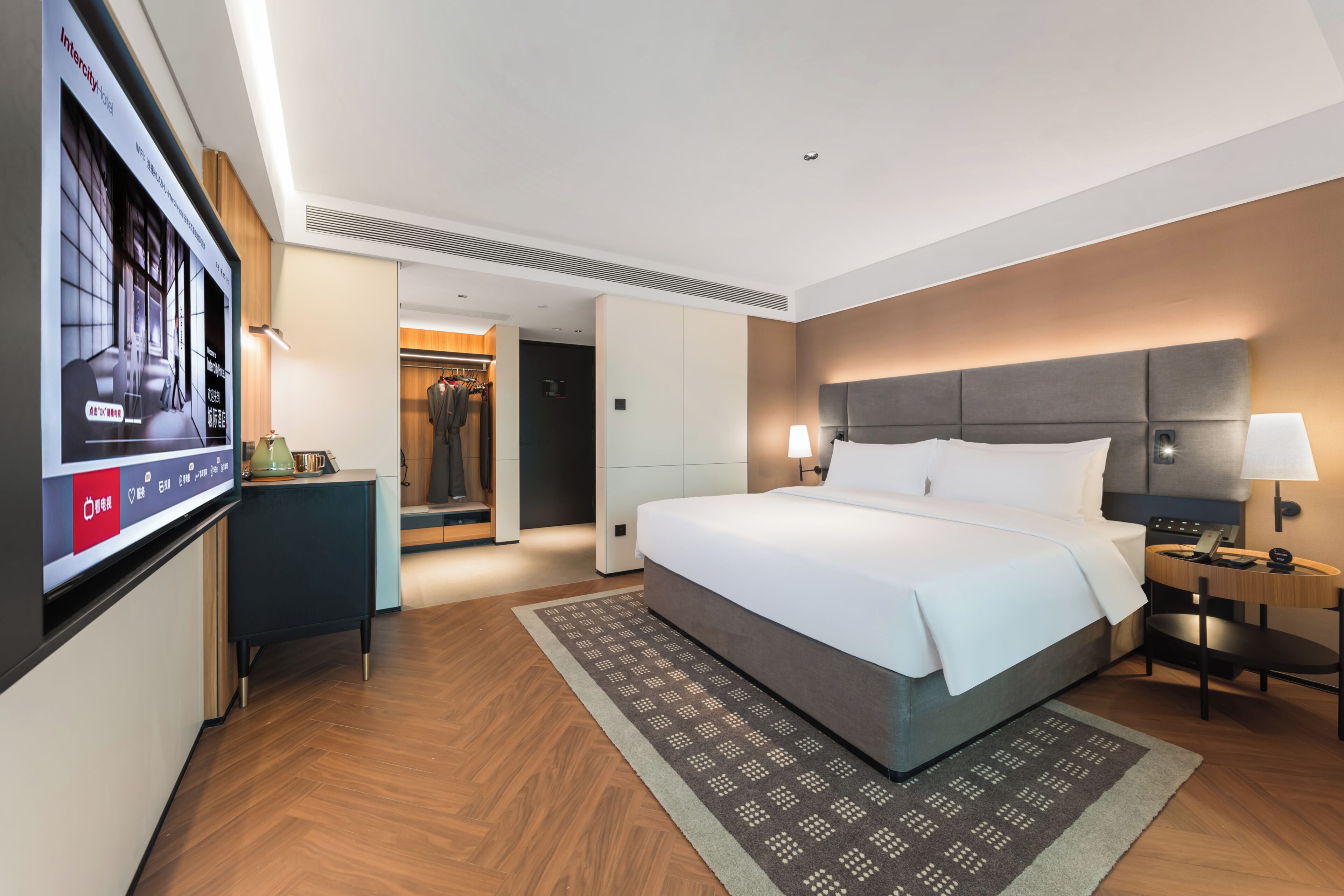 Una habitación de hotel con una cama grande, mesitas de noche, televisión y armario.