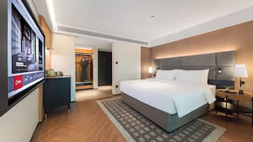 Una habitación de hotel con una cama grande, mesitas de noche, televisión y armario.