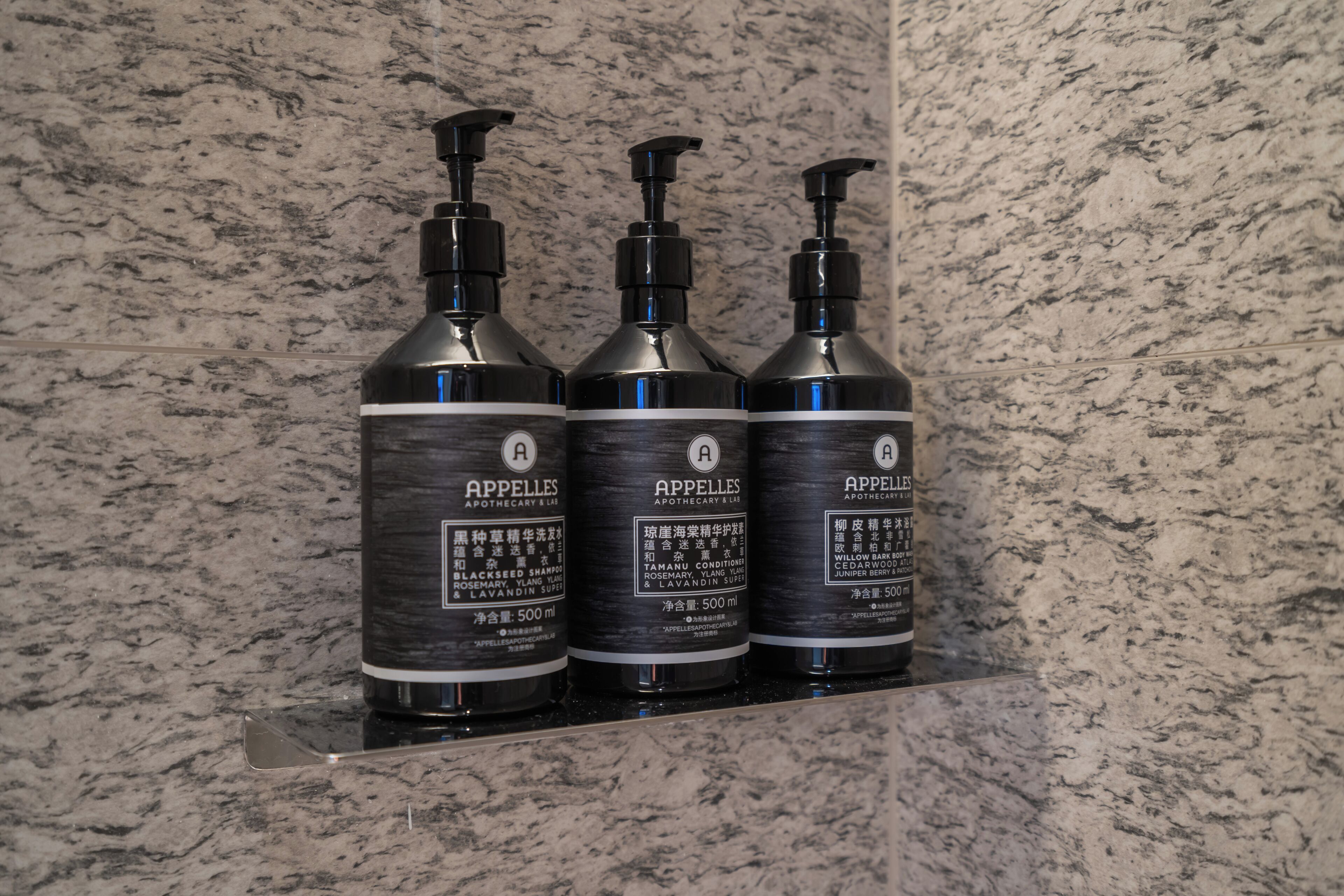 Tres botellas de APPELLES APOTHECARY LUM sobre un estante de mármol.