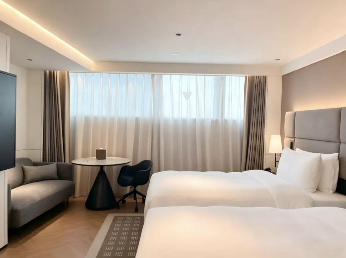 Habitació d'hotel amb llit, sofà, taula petita i televisió.