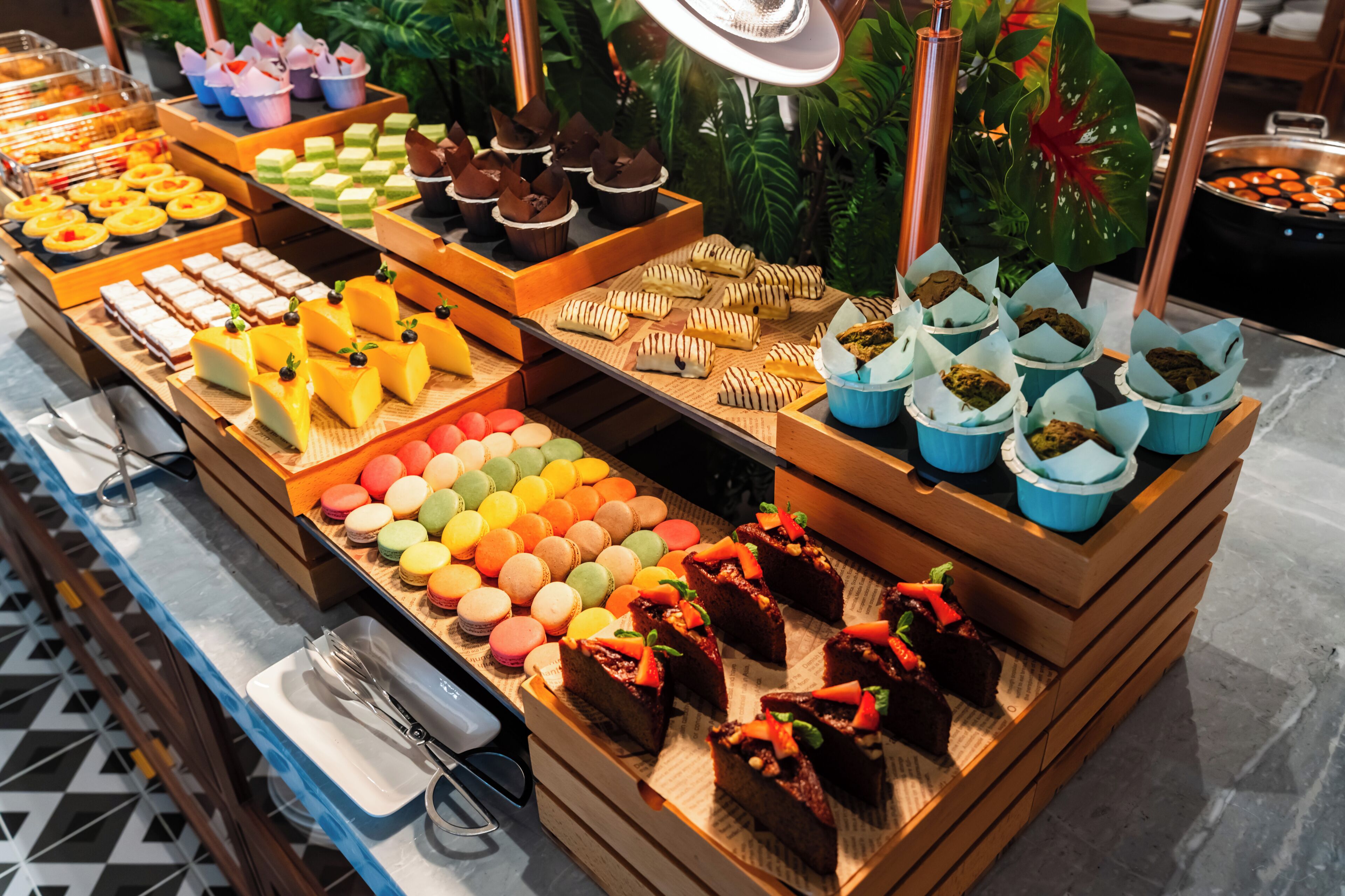 A buffet with various food items including pastries, macarons, and desserts.