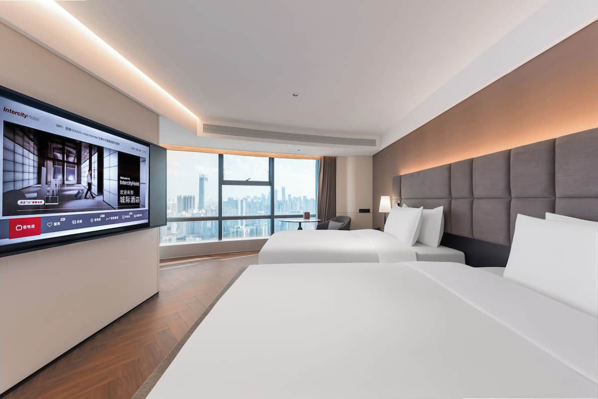 Hotelkamer met een grote televisie, twee bedden, stadszicht en modern design.