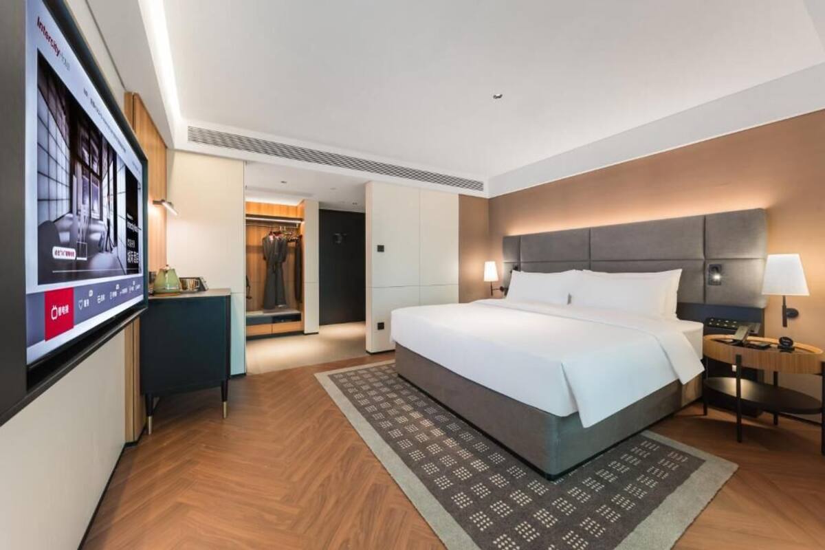 Een hotelkamer met een bed, nachtkastjes, een televisie en een kledingkast.