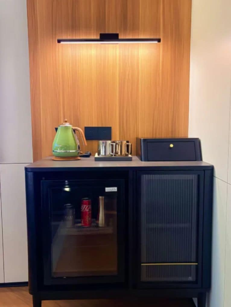 Een compacte minibar met een koelkast, koffiezetapparaat en waterkoker.