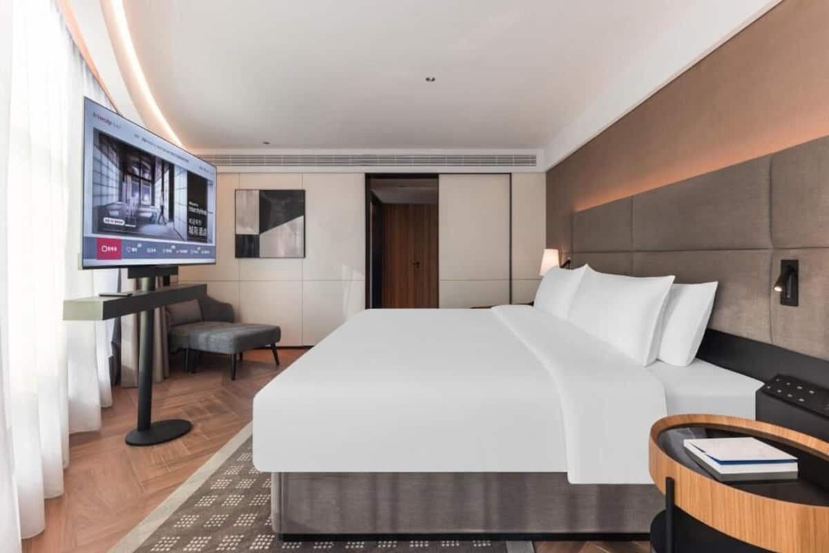 Een moderne hotelkamer met een groot bed, een televisie, een bureau en een stoel.