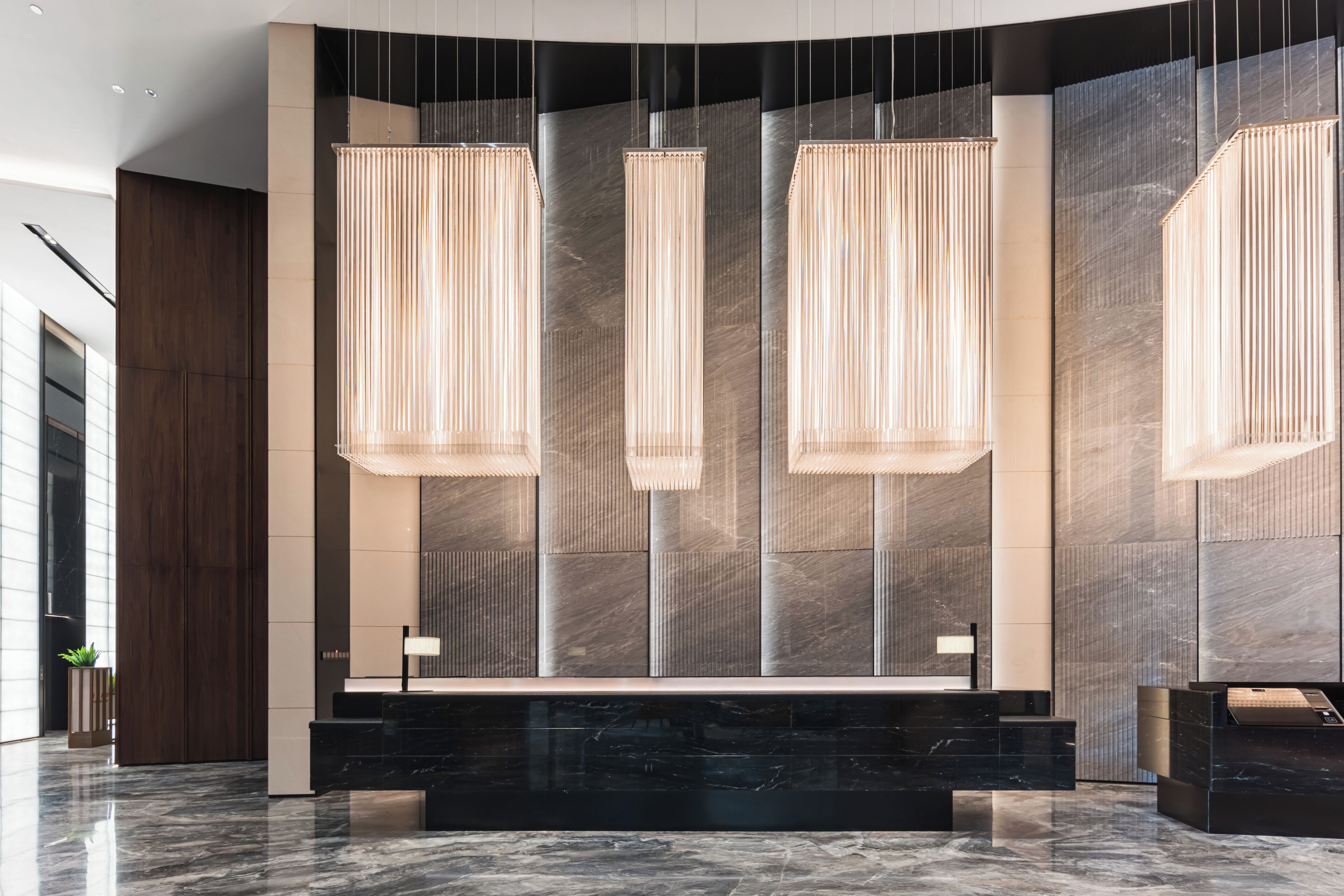 A modern reception area with a marble reception desk, vertical light fixtures, and a large wall with a textured pattern.