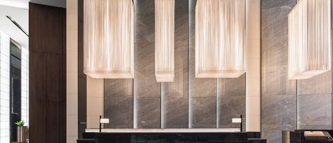 A modern reception area with a marble reception desk, vertical light fixtures, and a large wall with a textured pattern.