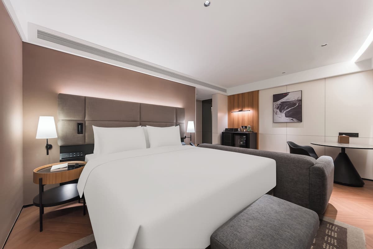 Een moderne hotelkamer met een groot bed, nachtkastjes, een bureau en een stoel.