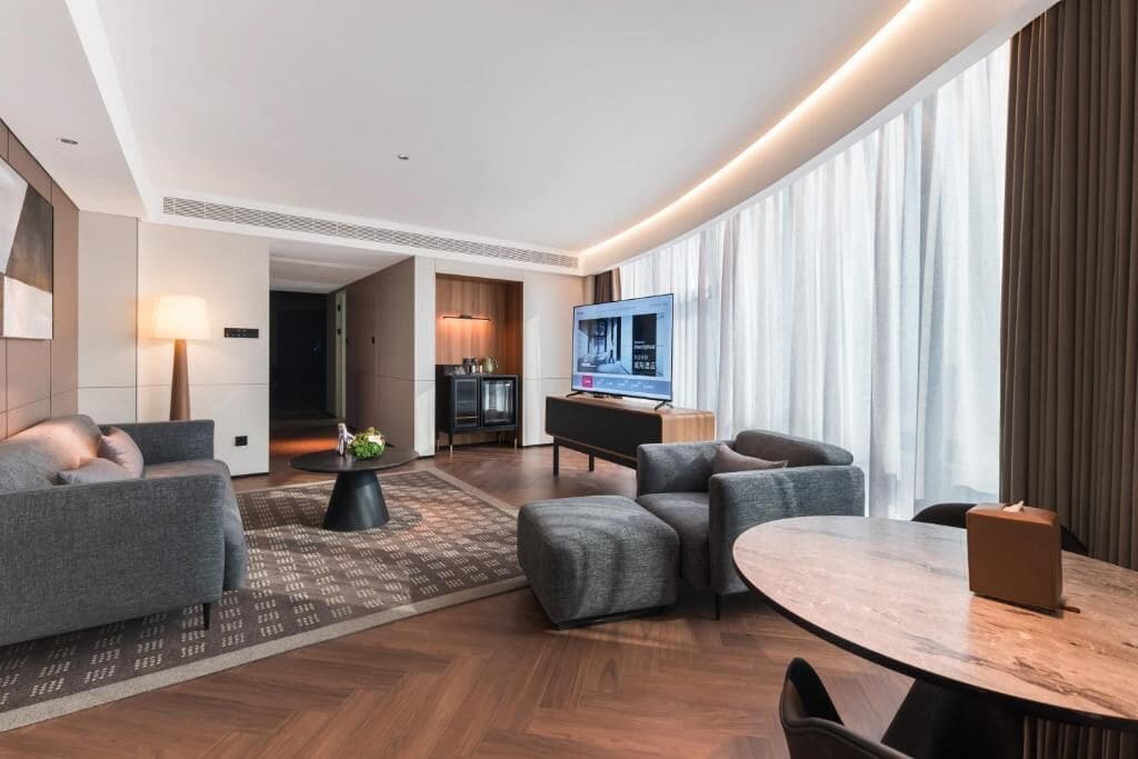 Une chambre d’hôtel moderne équipée d’un canapé, d’une table à manger, d’une télévision et d’un coin cuisine.