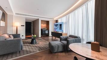 Ein modernes Hotelzimmer mit einer Couch, einem Esstisch, einem Fernseher und einer Küchenzeile.