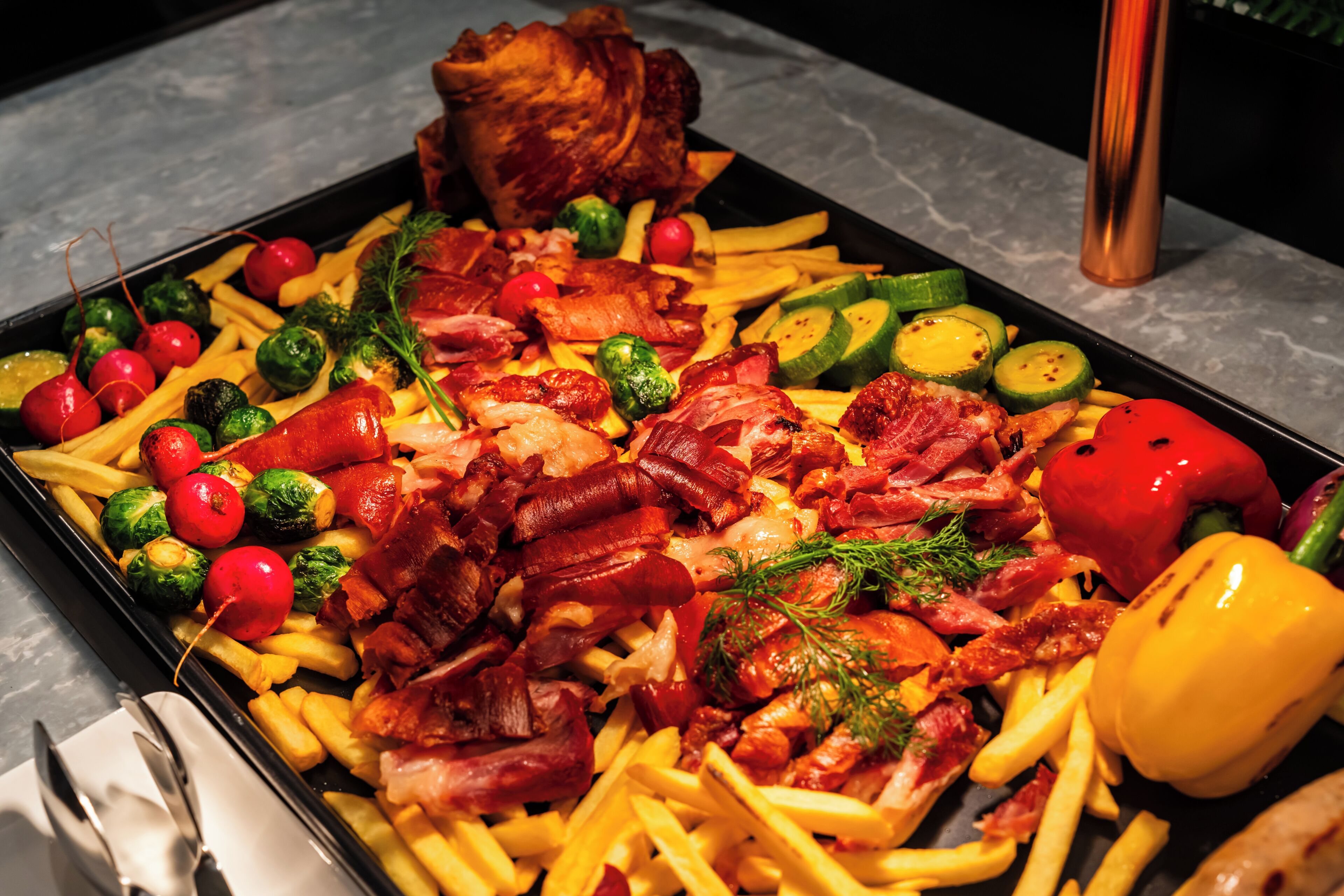 A tray of food with various items including meat, vegetables, and a bell pepper.