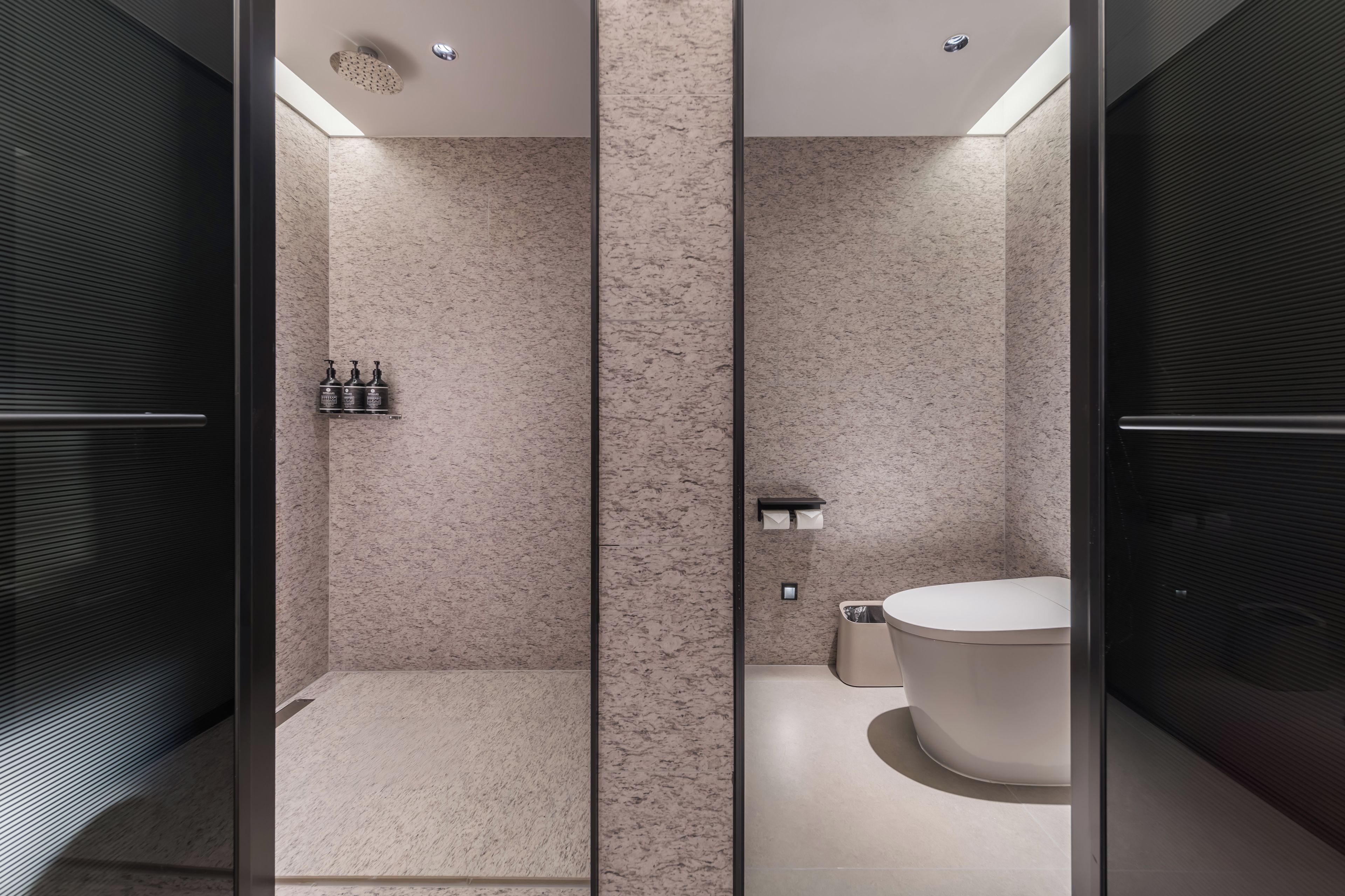 A modern bathroom with a glass partition, a freestanding bathtub, and a shower enclosure.