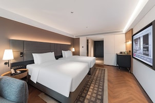 Una habitación de hotel con una cama grande, mesitas de noche, un escritorio y una pantalla de televisión.