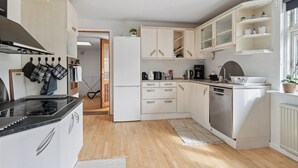 Moderni keittiö, jossa on valkoiset kaapit, sisäänrakennettu liesi, astianpesukone ja ikkuna, josta on kaunis näkymä.