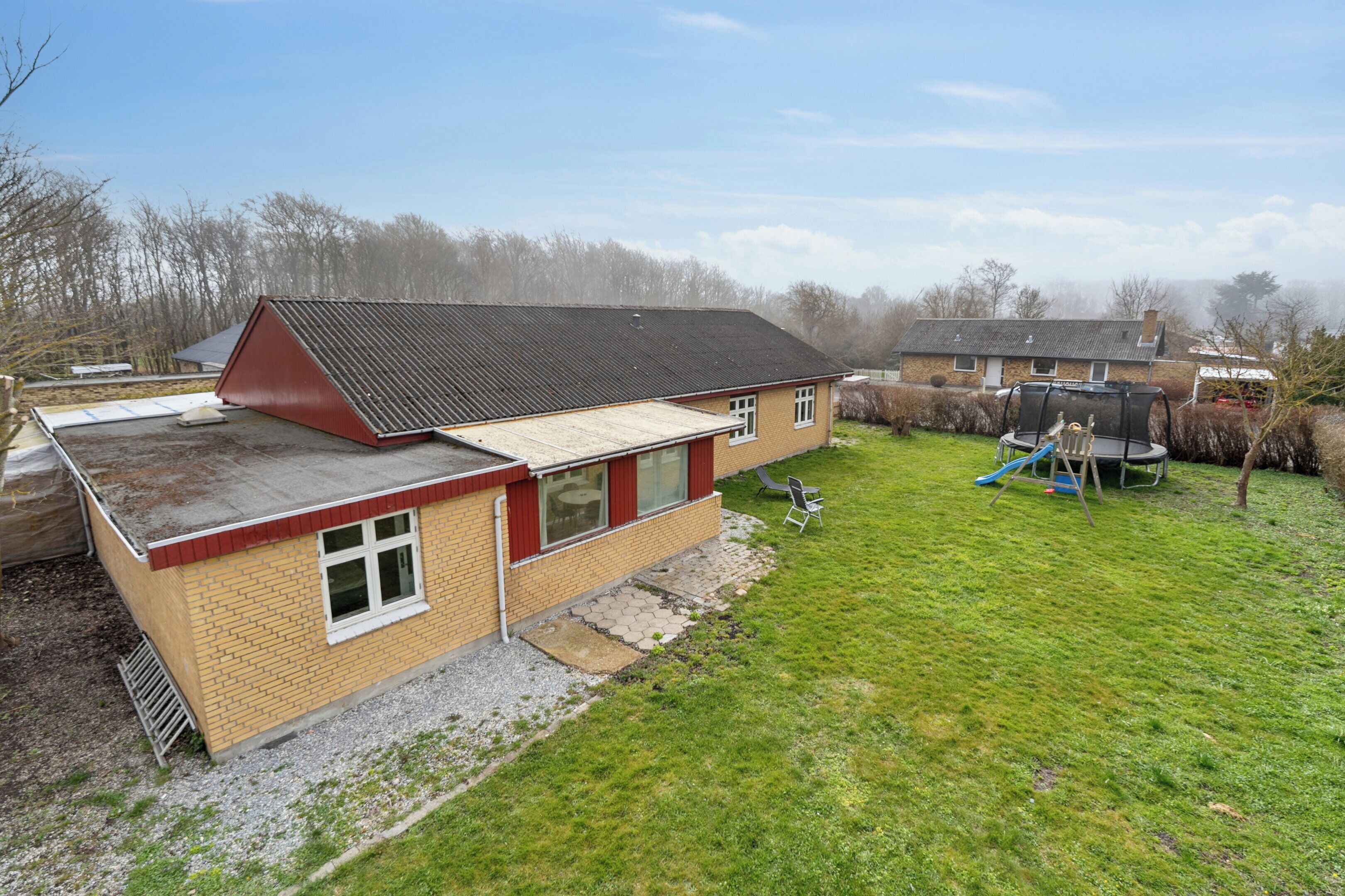 A single-story house with a red roof, a front porch, and a small front yard.