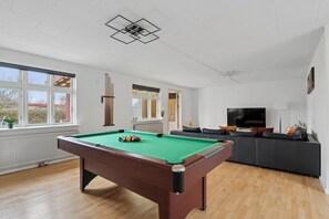 A pool table in a room with a sofa and a TV.