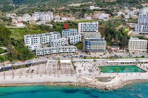 An aerial view of a coastal hotel with multiple buildings, a swimming pool, and a rocky shoreline. - Velaris Sea View Balcony 201 (Vlorë)