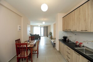 A modern kitchen with wooden cabinets, a black countertop, and a stainless steel sink. - Velaris Sea View Balcony 201 (Vlorë)