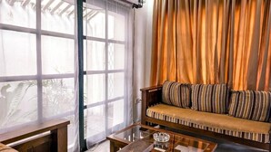 A room with a sofa, a glass coffee table, and a bench.