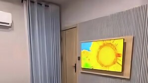 Ein Hotelzimmer mit Bett, Wandfernseher, Tür und Vorhang.