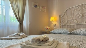 Un lit bien fait, avec des serviettes pliées, un coussin décoratif, une lampe de chevet et des œuvres d’art accrochées au mur.