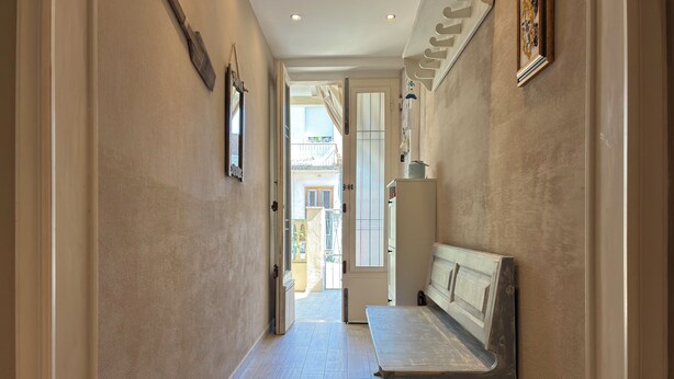 Un couloir avec un banc, une porte donnant sur l’extérieur et un cadre photo fixé au mur.