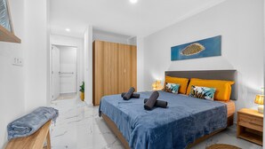 Ein Schlafzimmer mit Bett, Nachttischen, einer Bank, einem Kleiderschrank und einem Bild an der Wand.