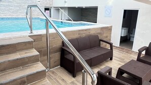 Zona de piscina con una escalera que lleva a un balcón, mobiliario de mimbre y vistas a la piscina.