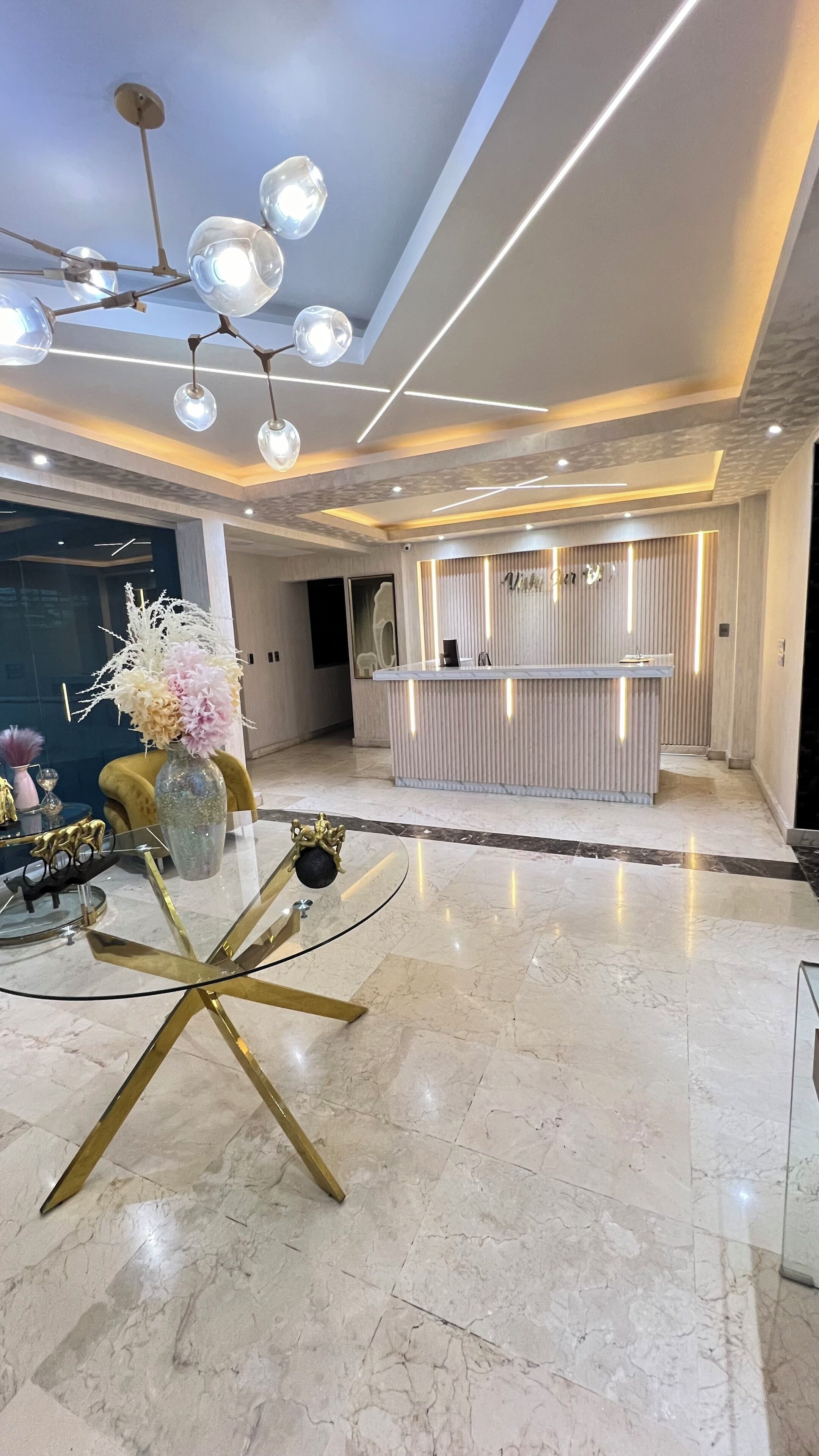 A modern hotel lobby with a reception desk, a glass coffee table, and a decorative vase.