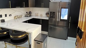 Una cocina moderna con una isla integrada, electrodomésticos de acero inoxidable y un cubo de basura compacto.
