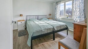 A bedroom with a bed, bedside tables, a chair, a window with curtains, and a radiator. - 1 bedroom stunning apartment in Vimmerby (Vimmerby)