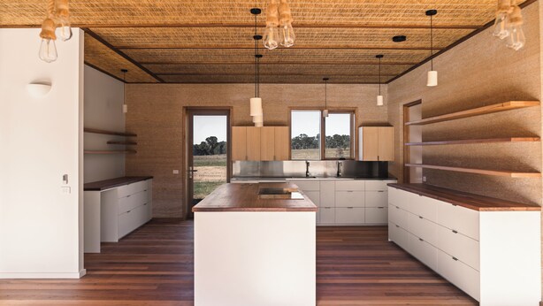 Eine moderne Küche mit Holzboden, weißen Schränken und Pendelleuchten.