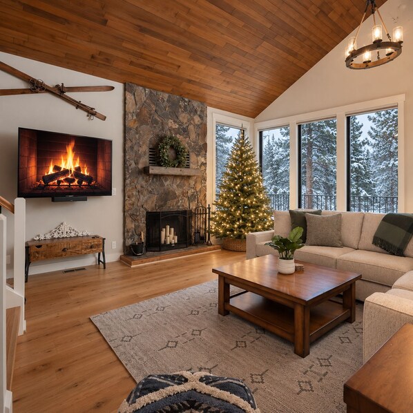 Een gezellige woonkamer met een open haard, een kerstboom en een groot raam met uitzicht op sneeuw.