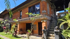 A two-story building with a balcony, a staircase, and a garden with various plants. - Kami House Ubud (Ubud)
