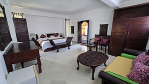 A hotel room with a bed, a sofa, a dining table, and a small round table. - Kami House Ubud (Ubud)
