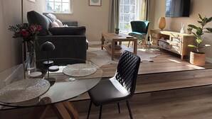Un soggiorno moderno con un divano, un tavolo da pranzo con sedie, una TV e una finestra con tende.